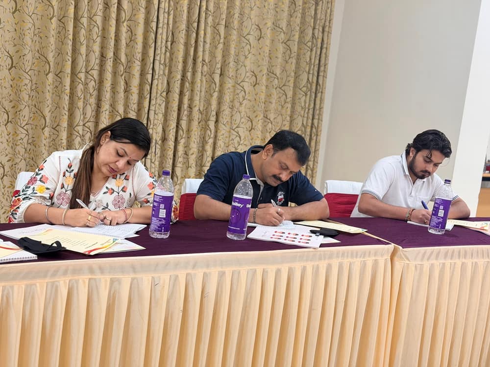 Three participants writing in Nurturing Souls workbooks at a draped table during a guided session