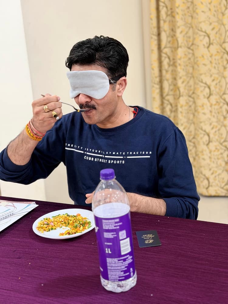 A participant wearing an eye mask eating slowly from a plate during a blindfolded mindful-eating exercise