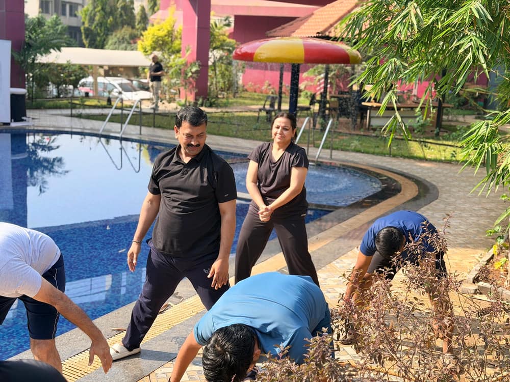 Participants in activewear practising a grounding exercise on the paving beside an outdoor pool