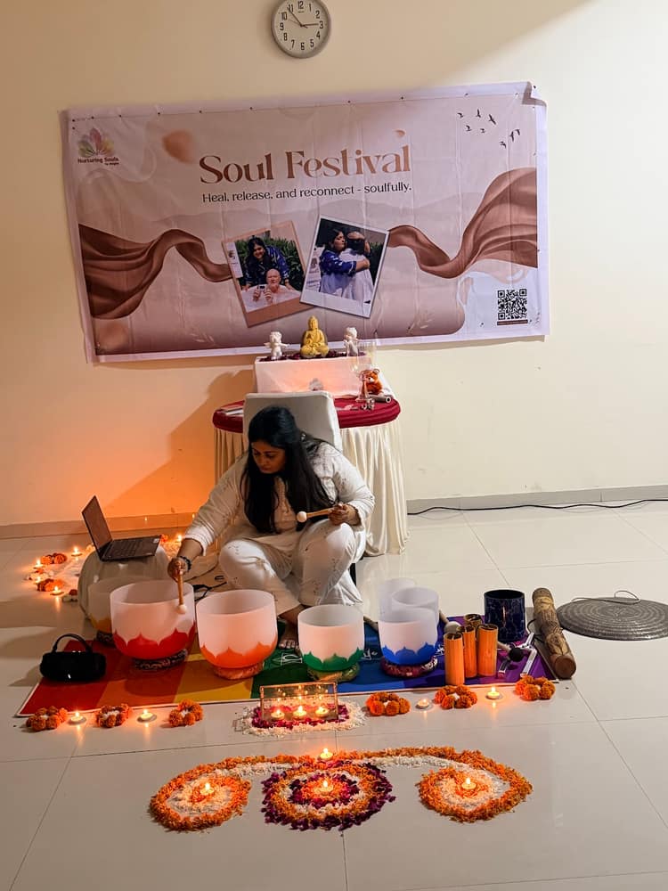 Crystal singing bowls, lit diyas and a rangoli arranged on the floor before a sound bath begins